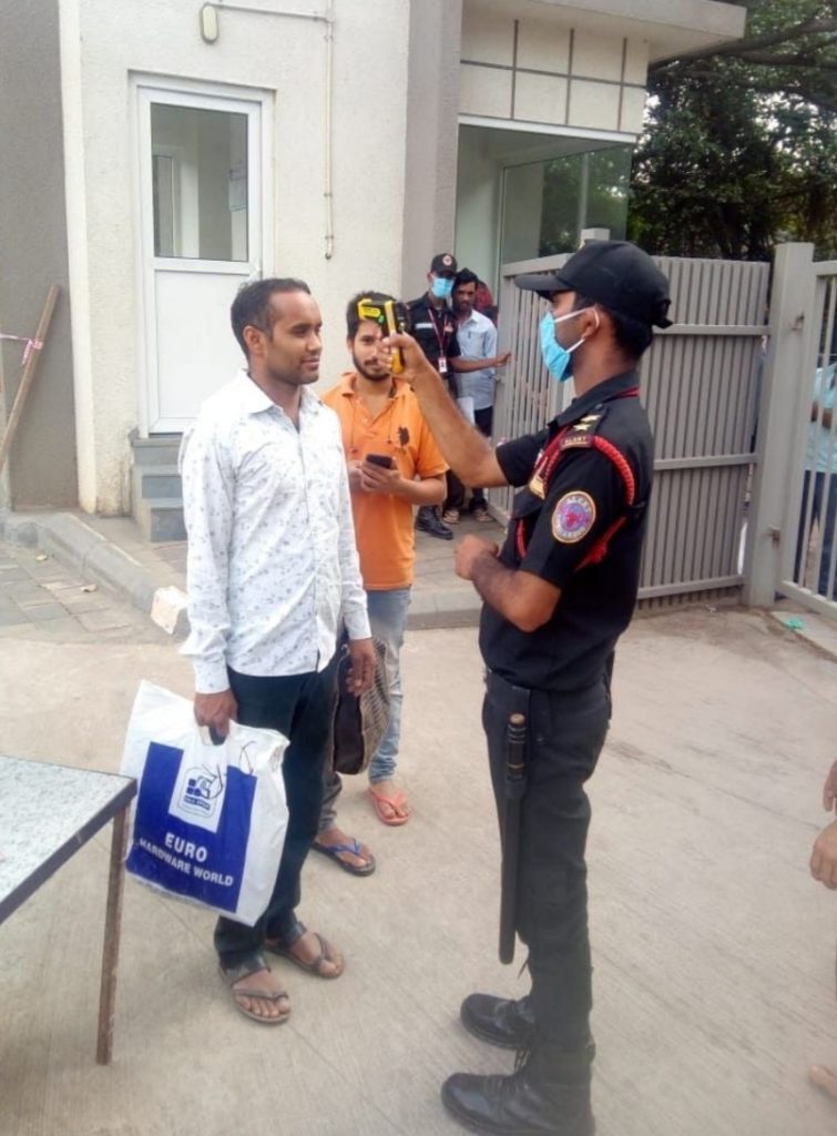 Guards measuring body temperature of the staff at the main gate to avoid COVID-19 